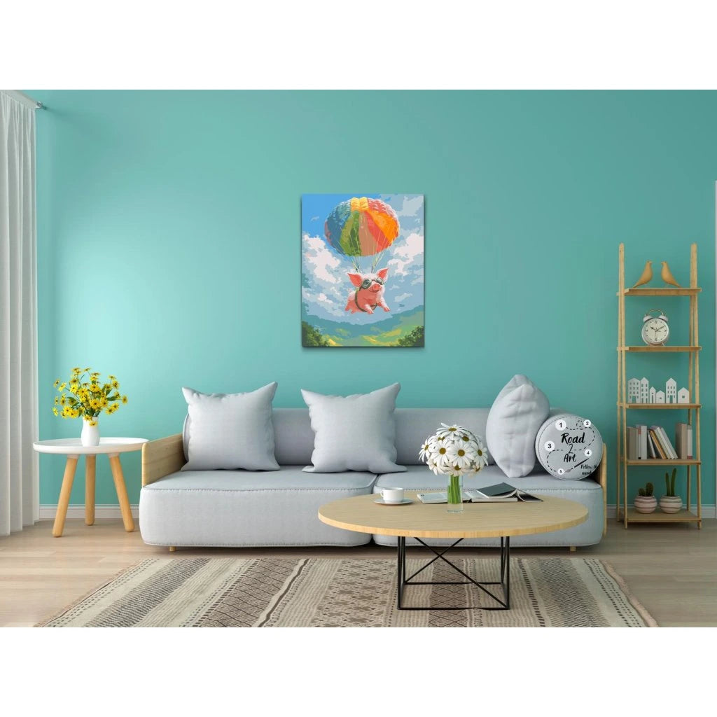 Maleftertal motiv af en flyvende gris med faldskærm over landskab og blå himmel